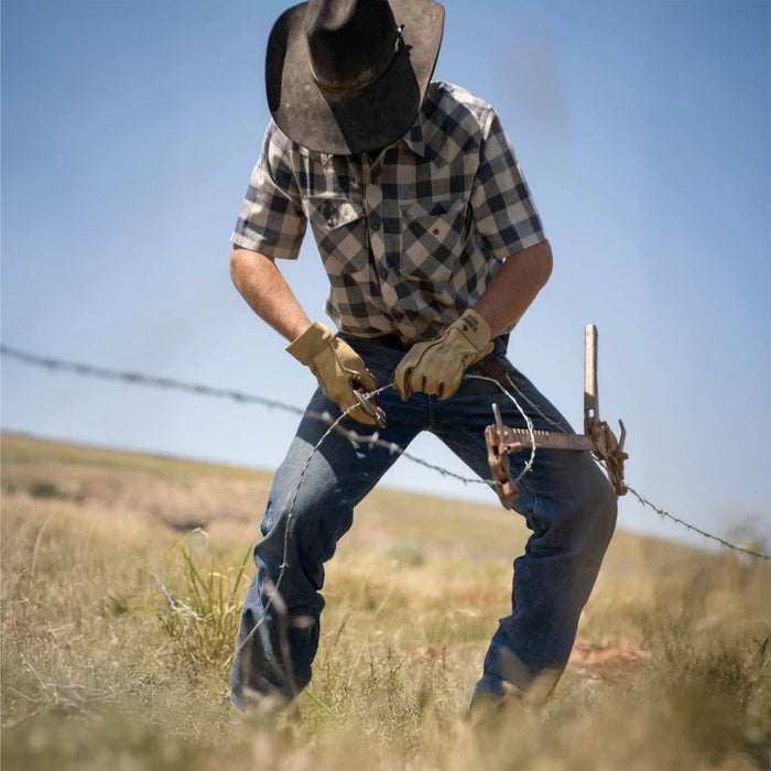 A man is working on farm field fence wire