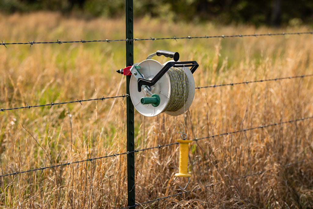 Utilizer poly wire reel holder mounted on a T-post for electric fence